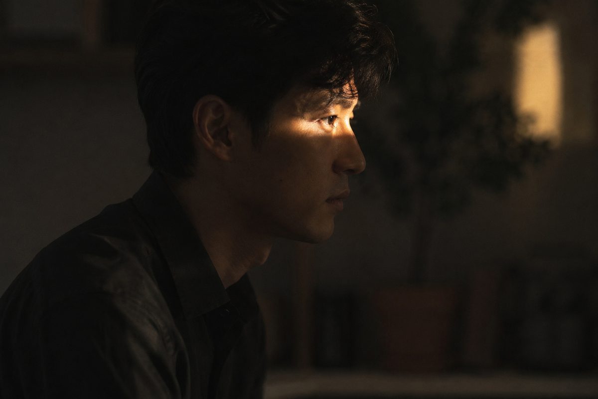 A man in profile, lit by a single streak of warm light